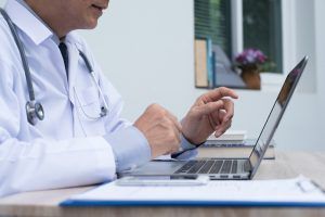 doctor helping patient over laptop