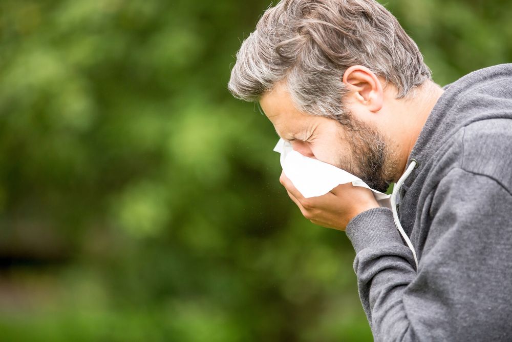 man sneezing into tissue